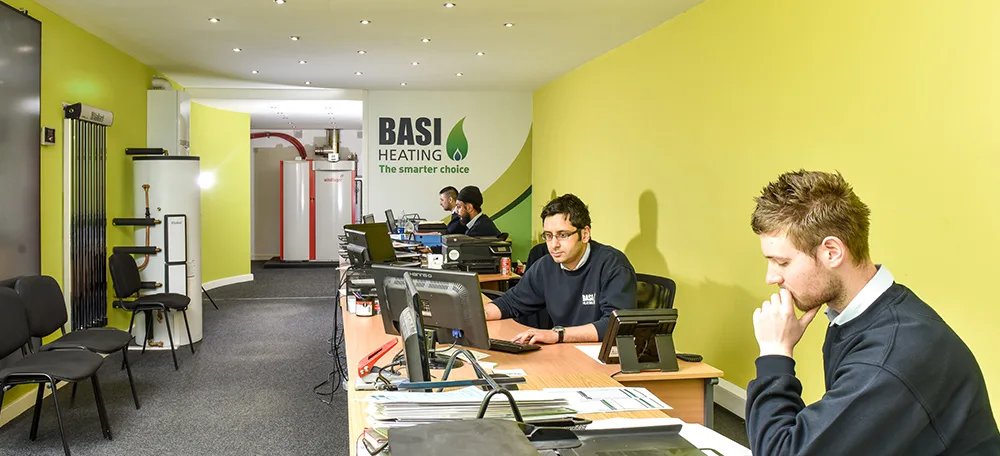 The BASI Heating team at work in the Bradford office, with heating cylinders and boilers on display